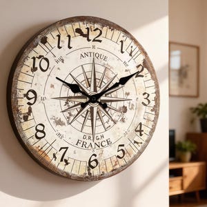 Puede incluir: Un reloj de pared redondo de estilo antiguo con un acabado envejecido. La esfera es blanquecina con números y manecillas negras. Un diseño de rosa de los vientos está en el centro y el texto "FRANCE" es visible.