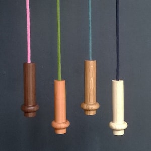 May include: Four wooden light pull switch cords with different coloured cords. The cords are pink, green, blue, and black. The wooden pulls are brown, orange, natural wood, and light wood.