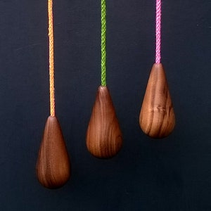 May include: Three wooden teardrop-shaped light pull chains with different coloured cords. The cords are orange, green, and pink.