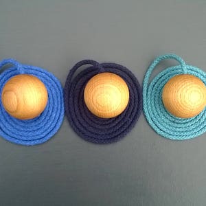 May include: Three wooden balls with rope wrapped around them. The ropes are blue, dark blue, and teal.