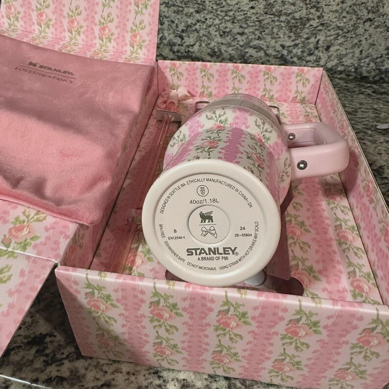 May include: A pink floral Stanley mug with a handle, presented in a matching gift box. The mug has a capacity of 40oz/1.18L. The box and mug feature a pink floral pattern. The mug is designed in Seattle, WA, and manufactured in China.