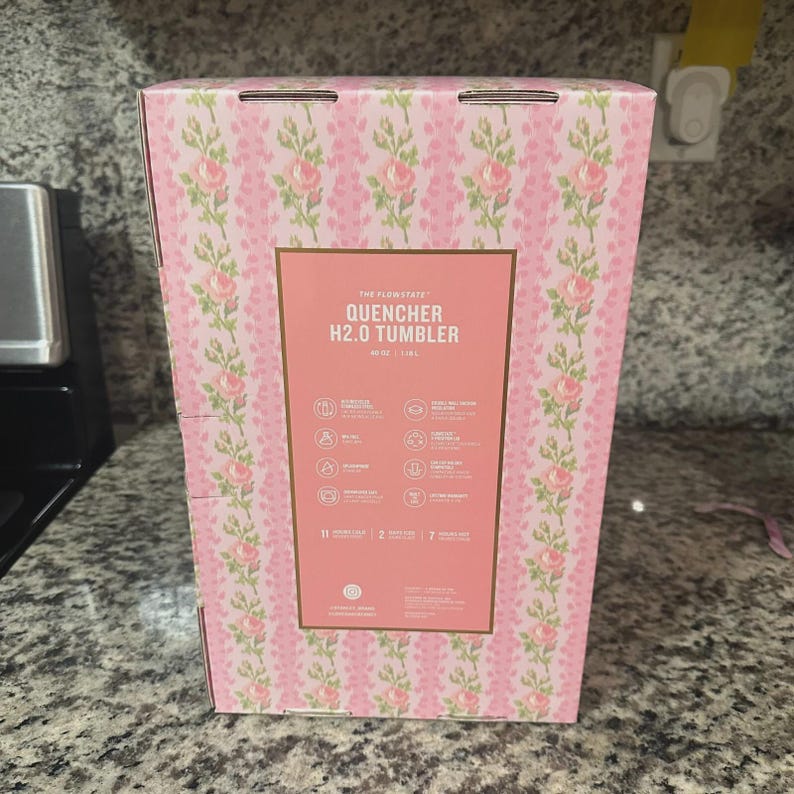 May include: A pink box with a floral pattern and the text "QUENCHER H2.0 TUMBLER". The box has a rectangular label with product information and icons. The tumbler holds 40 oz, or 1.18 L.