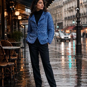 May include: A blue and white textured blazer with a notched collar and single button closure, worn over a black turtleneck sweater and black trousers with black leather shoes, creating a layered outfit with a structured silhouette and long sleeves.