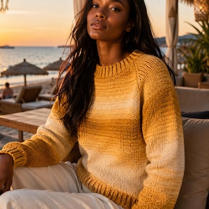 May include: A long-sleeved knit sweater featuring a horizontal ombre gradient pattern that transitions from deep golden yellow at the shoulders and cuffs to a lighter cream color across the midsection, finished with a ribbed crew neckline.