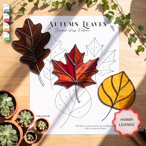 Może przedstawiać: Arkusz wzorów zatytułowany Autumn Leaves Stained Glass Pattern z trzema gotowymi szklanymi liśćmi w kolorze brązowym, czerwonym i żółtym, obok rysunków liniowych z ponumerowanymi sekcjami i odznaką Hobby Licence.