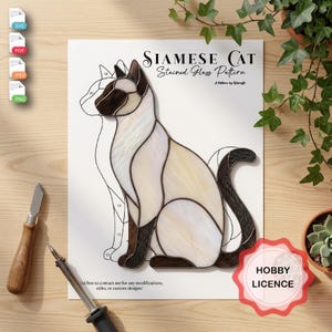 May include: A Siamese cat stained glass pattern printed on white paper. The design features a seated cat with cream-colored body segments and dark brown ears, face, and tail. The text reads Siamese Cat Stained Glass Pattern, A Pattern by Kolarcraft, and Hobby Licence.
