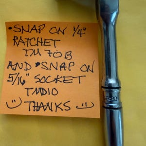 May include: A silver Snap-on ratchet with a 1/4" socket attached. The handle is smooth and ergonomic. A handwritten note on an orange sticky note reads "SNAP ON 1/4" RATCHET TM70B AND SNAP ON 5/16" SOCKET TMDIO THANKS".