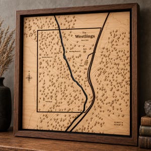 May include: A square wooden wall art piece featuring a laser-engraved topographic map of land. The map displays the text The Westlings Since 2026, with labels for Hunting Shack 1, Hunting Shack 2, Barn, House, and Tree Stand.