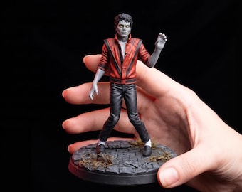 May include: A detailed figurine of a zombie-like figure with gray skin and yellow eyes, wearing a red leather jacket with black accents, a white shirt, black pants, and black loafers, standing on a circular stone-textured base with debris.