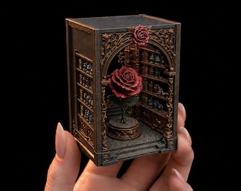 May include: A miniature diorama box featuring a dark gray and bronze-toned structure with an arched entryway. Inside, a single large red rose sits on a circular pedestal, surrounded by shelves filled with tiny jars and bottles on the side walls.