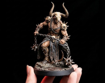 May include: A detailed figurine of a muscular warrior with a horned skull helmet and spiked armor. The figure holds two spiked maces connected by chains. The base is a stone-like texture, and the overall color palette is earthy tones with metallic accents.