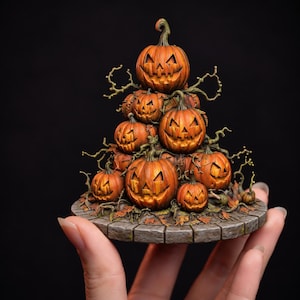 Może przedstawiać: Miniaturowa rzeźba przedstawiająca stos wyrzeźbionych pomarańczowych dyń z trójkątnymi oczami i wyszczerbionymi ustami, ozdobiona brązowymi, poskręcanymi gałązkami i rozrzuconymi jesiennymi liśćmi na okrągłej podstawie o fakturze szarego kamienia.