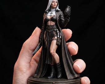 Pode incluir: Estatueta detalhada de uma freira em traje de couro preto, segurando uma granada e uma faca. A figura tem um hábito branco e um colar com uma cruz. A base é redonda com uma cruz.