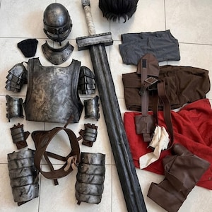 May include: A cosplay costume set including a metallic gray chest plate, shoulder pauldrons, arm guards, leg greaves, a helmet, and a large sword. The set also features a black wig, a red fabric piece, brown leather-like straps, and dark gray clothing.