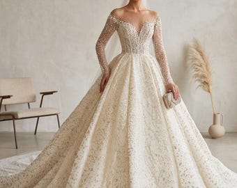 Könnte beinhalten: Ein elfenbeinfarbenes Hochzeitskleid mit weitem Rock und langen Ärmeln. Das Oberteil und die Ärmel sind mit glitzernden Perlen verziert. Das Kleid hat einen tiefen V-Ausschnitt und eine lange Schleppe. Eine kleine, goldene Clutch wird gehalten.