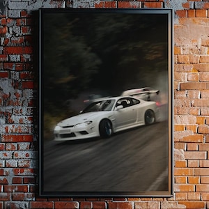 May include: A framed wall art print featuring a white sports car drifting on a dark asphalt road. The car is captured in motion with a blurred background of trees. The print is enclosed in a thin black frame and displayed on a rustic red brick wall.
