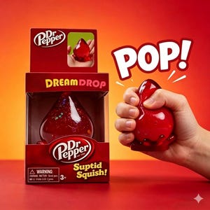 May include: A red Dr. Pepper Dream Drop toy in a box with the text "Suptid Squish!". The image shows a hand squeezing the toy, with the word "POP!" in white letters. The box has the Dr. Pepper logo.