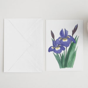 May include: A white card with a watercolor illustration of purple irises with yellow centers. The irises are arranged in a bouquet with green leaves.