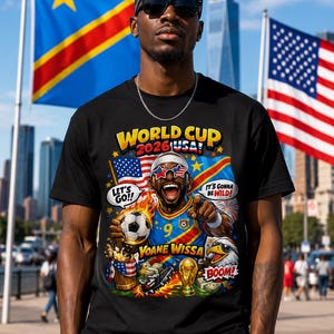 May include: Black t-shirt with a colorful graphic celebrating the 2026 World Cup in the USA. The design includes the text "World Cup 2026 USA!" and an illustration of a soccer player. The shirt also features the text "Let's Go!!" and "It's Gonna Be Wild!"