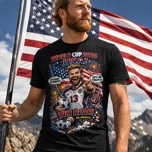 Pode incluir: Uma t-shirt preta com um gráfico de um jogador de futebol e o texto World Cup 2026 USA, Tim Ream, Mr America, I'm Ready To Rock e Let's Go Crazy. O design inclui bolas de futebol, fogo de artifício e uma bandeira americana.