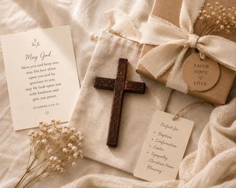May include: A wooden cross, gift box with a ribbon, and a card with text are arranged on a beige fabric. The gift box has a tag that says "Faith Hope Love." The card reads "May God bless you and keep you..." and lists occasions.