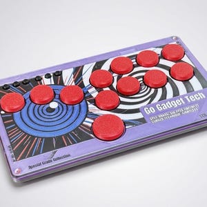 May include: A rectangular arcade game controller with a purple base and red buttons. The controller has a graphic design with blue and white swirls and the text "Go Gadget Tech". The controller is a Special Grade Collection item.