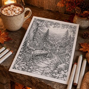 May include: A black and white line art illustration on paper depicting a forest scene with a wooden bench, a winding path, and dense trees. The drawing is surrounded by a mug of hot cocoa with marshmallows and several colored art markers.