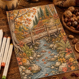 May include: A detailed colored pencil drawing of a wooden bridge spanning a rocky stream in an autumn forest. The scene features vibrant orange and yellow maple leaves, evergreen trees, and ferns. Three Ohuhu art markers lie beside the artwork.