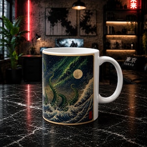 May include: A white ceramic mug featuring a detailed graphic illustration of green tentacles emerging from turbulent blue ocean waves under a starry night sky with a full moon. The artwork has a distinct woodblock print aesthetic.