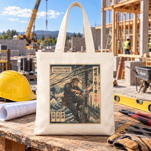 May include: A cream-colored canvas tote bag featuring a graphic print of a utility worker on a power pole. The design includes Japanese text, a stylized wave, and the English words THUNDER ORDER and Voice of Thunder.