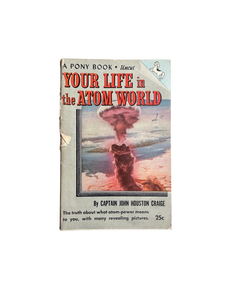 Pode incluir: Um livro de bolso vintage intitulado Your Life in the Atom World por Captain John Houston Craige. A capa apresenta uma ilustra&ccedil;&atilde;o de uma nuvem at&ocirc;mica, texto em vermelho e preto, um pequeno gr&aacute;fico de um p&ocirc;nei e o pre&ccedil;o de 25c na base.