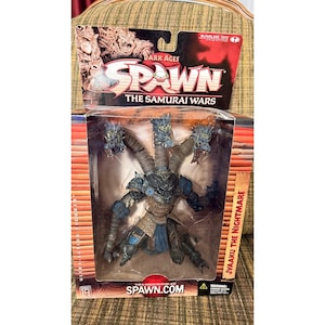 Peut inclure: Une figurine McFarlane Toys Dark Ages Spawn The Samurai Wars Jyaaku The Nightmare dans son emballage d'origine. La figurine représente une créature à plusieurs têtes avec une armure bleue et brune, des cous segmentés et des têtes de dragon.