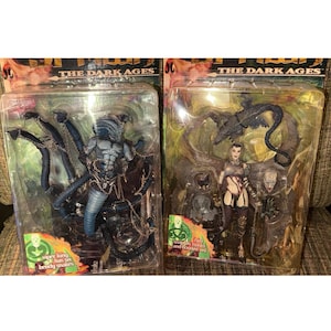 Puede incluir: Dos paquetes blíster de figuras de acción de Spawn The Dark Ages. El paquete izquierdo contiene una figura azul de Viper King con seis serpientes flexibles y cadenas. El paquete derecho contiene una figura femenina con dos máscaras, un velo y un dragón.