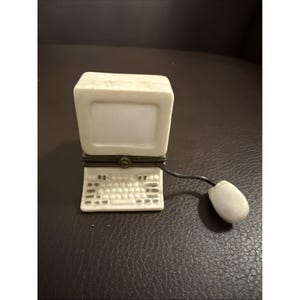 May include: A white ceramic trinket box shaped like a vintage desktop computer with a monitor and keyboard. The box features a brass-colored metal hinge at the center and a small white computer mouse attached by a thin black cord to the side.