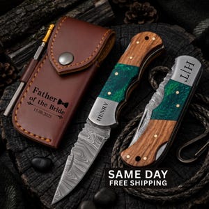 May include: A brown leather sheath with the text Father of the Bride 15.08.2025, a folding knife with a Damascus steel blade and wood and green resin handle engraved with HENRY, and a second folded knife with the initials H|T on the metal bolster.