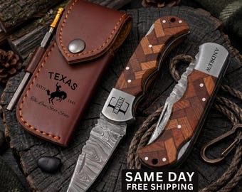 May include: A brown leather sheath with a Texas logo, a folding knife with a herringbone wood handle and Damascus steel blade engraved with the name Ethan, and a second folding knife with a herringbone wood handle engraved with the name Andrew.