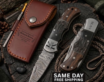 May include: Two folding knives with dark wood handles and patterned steel blades, one open and one closed, alongside a brown leather sheath. The sheath is engraved with "In Loving Memory Of Richard Brown" and the open knife blade features "KADE".