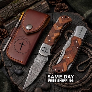 May include: A brown leather sheath with a cross and text, a folding knife with a herringbone wood handle and a Damascus steel blade engraved with the name Ryan, and a second folding knife with the name Robert engraved on the metal bolster.