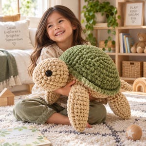 Op de afbeelding: Een grote, handgemaakte gehaakte schildpadknuffel met een textuurrijk, mosgroen schild en een crèmekleurige kop, ledematen en onderkant. De schildpad heeft één zichtbaar zwart plastic oog en is gemaakt van dik, zacht garen in een grove breistijl.