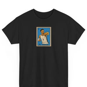 Puede incluir: Una camiseta negra con un estampado gráfico rectangular de un jugador de baloncesto con camiseta blanca y el número 1, realizando un codazo. El gráfico tiene estilo de carta de juego con el texto EL CODAZO y el número 1.