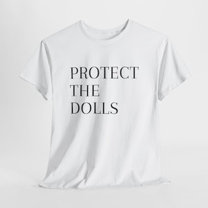 Può includere: T-shirt bianca con la scritta nera "PROTECT THE DOLLS" centrata sul davanti. La maglietta ha maniche corte e girocollo. Il tessuto sembra essere morbido cotone o misto cotone.