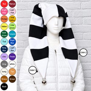 May include: A long, two-toned jester hat featuring horizontal black and white stripes. The hat has two long, pointed tails hanging down, each finished with a small silver-colored metal bell at the tip. A color chart is visible on the left side.