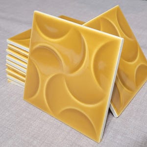 Peut inclure: Carreaux de céramique jaune moutarde, de forme carrée, avec un motif semi-circulaire en relief. Les carreaux ont une finition brillante et des bords blancs. Convient aux cuisines, salles de bains ou autres utilisations décoratives. Mesure environ 15 cm x 15 cm.
