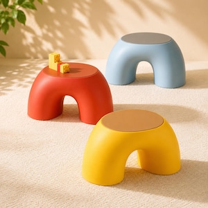 May include: Three contemporary stools in red, blue, and yellow. Each stool features a rounded, arch-shaped base and a circular top. The red stool has a small toy on top. The stools are on a neutral carpet.