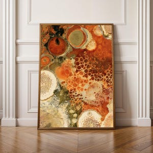 Könnte beinhalten: Ein rechteckiger Wandkunstdruck in einem Holzrahmen mit einem abstrakten Fluid-Painting in einer warmen Farbpalette aus gebranntem Orange, tiefem Rost, Olivgrün und Creme. Die Komposition zeigt organische kreisförmige Muster und zellartige Strukturen.