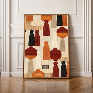 Op de afbeelding: Een rechthoekig wandkunstwerk met een getextureerd vezelkunstontwerp met diverse garenvormen en kwastjes in tinten van gebrand oranje, crème, beige en zwart. De compositie bevat gelaagde geometrische vormen en hangende franje-elementen.