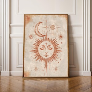 May include: A rectangular wall art print in a wooden frame featuring a terracotta-colored illustration of a sun with a human face and closed eyes, surrounded by a crescent moon, smaller stars, and radiating sunbeams on a textured beige background.