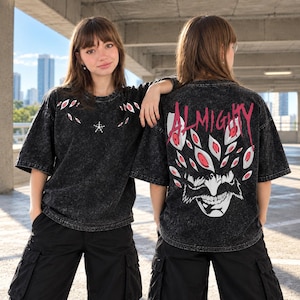 May include: A black acid-wash t-shirt featuring a small star symbol and scattered eye graphics on the front. The back displays a large graphic of a grinning face surrounded by numerous eyes and the word ALMIGHTY in bold red lettering.