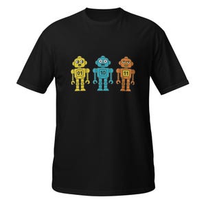 May include: Black t-shirt featuring three retro robot illustrations in yellow, blue, and orange. Each robot has a unique number: 01, 10, and 11. The robots have a classic, cartoonish design with simple shapes and details.