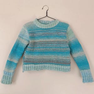 Jersey de punto a rayas azul menta y plata, tejido degradado teñido en segmentos con hilo brillante.